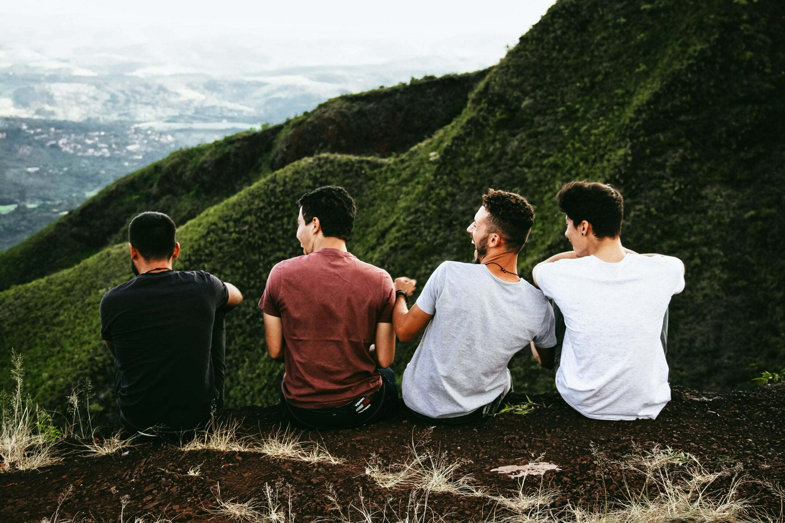 Men Travel in a Group tour laughing by green valley. By Matheus Ferraro - Unplash